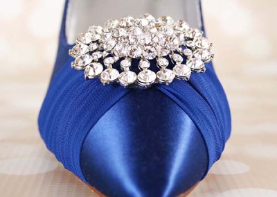 Hi Shelley,   Your dress is gorgeous!  Thanks for sharing!  No problem using email at all!  Let’s get started!   I know that you said that you were going to look through some of the links I provided, but I did spend some time looking at your initial request and put together some ideas based on that, but we can explore as many ideas and options as you would like.    For your design, I see that you picked the Flash shoe, which is actually a 3 ½” heel, so I wanted to make some recommendations that are a little less than 3 ½” for the base shoe.  I included them below.  Please note that we measure heel height from the inside of the heel and not the back of the shoe up.  I like Addison a lot for you, as it’s about the right heel height and it has got some sparkle on the toe of the shoes.  If you like it, I was thinking that we could do that shoe in Lapis with a painted sole (did you have a contrasting color that you wanted to use? or we could do silver or gold if you want something neutral) and then do the “Save the Date” also in Lapis.  I attached some font options for that.  As far as the charm goes, the sky is the limit!  We can pretty much do anything you like!  There are a variety of ways to attach it, but I included some examples below.  Let me know what you think!    In terms of next steps, I like to continue the process of sharing ideas and images, so let me know what you like and what you don’t, how close we are on budget and any other thoughts or ideas that you have.  Once we get the design details refined, you’ll have the option of having our in-house artist complete a sketch for you of your shoes and/or participating in The Perfect Fit program.  If you’d like to move forward with the production of your shoes, we can do that too, as not all brides want to do The Perfect Fit or the sketch and that’s totally fine!    Best, Kate    	  Photo 1: 	  Photo 2: 	  Photo 3: 			 	   Photo 4:	   Photo 5:	   Photo 6: 	Blue Wedding Shoes Closed Toe Bridal Heels Chiffon Sash and Crystal Brooch